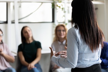 women listen to another woman during a meeting