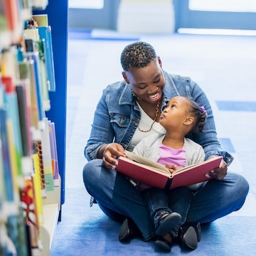 african amercian father reading to daughter
