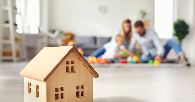 Wooden house in focus with a family playing in the background