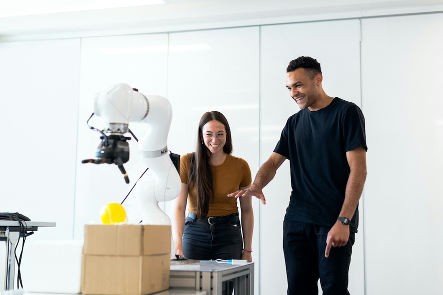 Two doctoral students looking and discussing robotics and AI automation