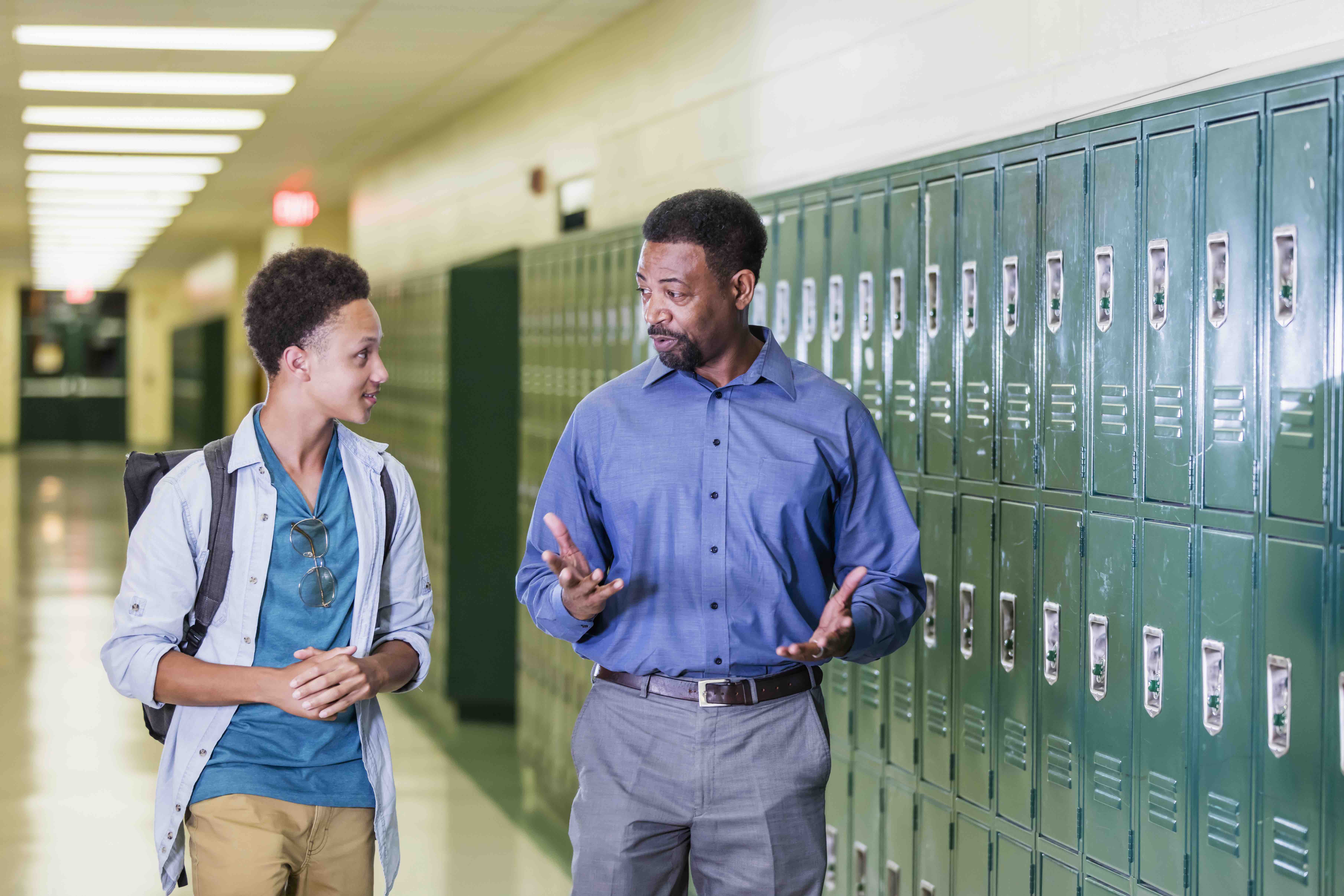 principal talking to student in school hallway