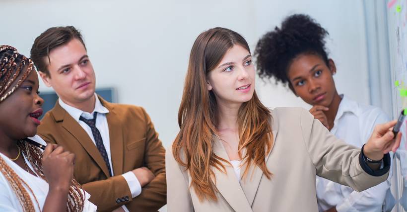 Woman speaking with coworkers in front of whiteboard