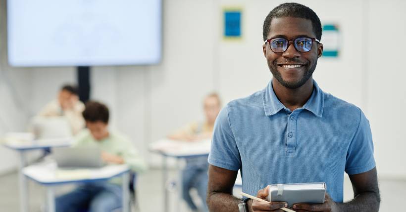 Smiling teacher holding notebook.