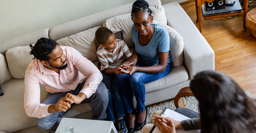 Family sitting on couch speaking to therapist