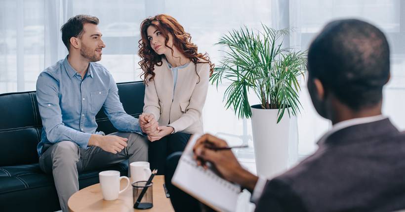 Therapist speaking to a couple holding hands