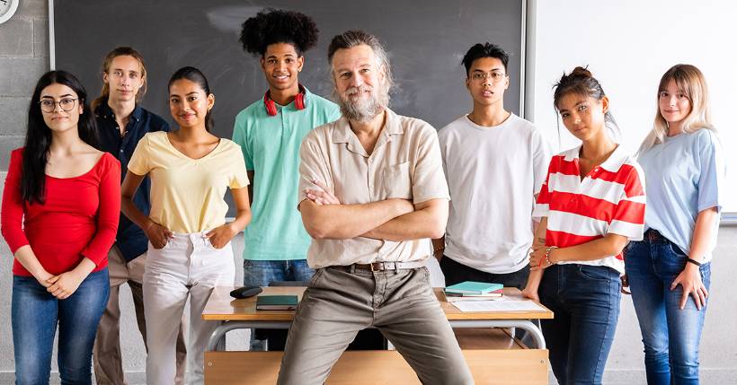 Teacher at front of class with students standing behind