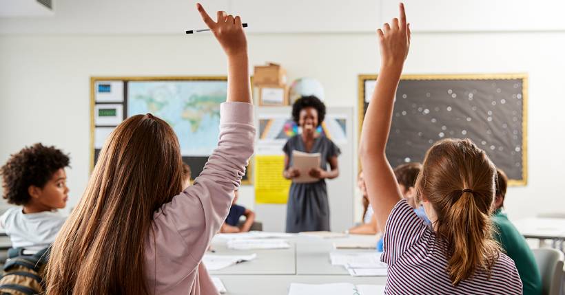 Two students raising hands in class