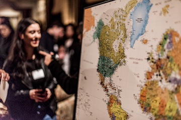 doctoral student talking off to the side by a world map