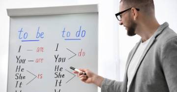 Teacher standing in front of a whiteboard teaching his students