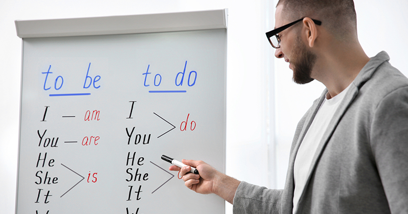 Teacher standing in front of a whiteboard teaching students