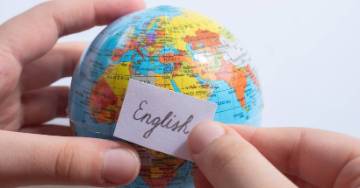 Person holding a small globe with a note that says English on it