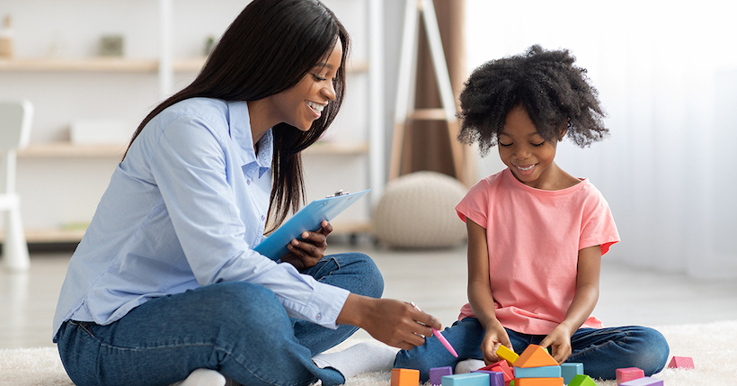 Behavior analyst observing child playing with blocks