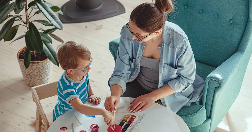 Woman helping child paint