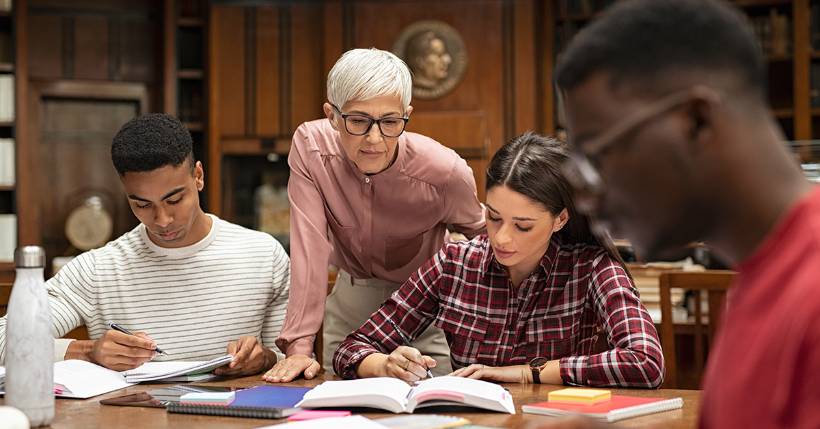 Teacher overviewing work of two students.