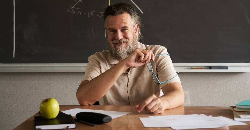 Teacher sitting at his desk smiling