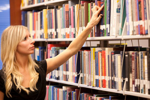 A woman browses through library books - Pepperdine GSEP