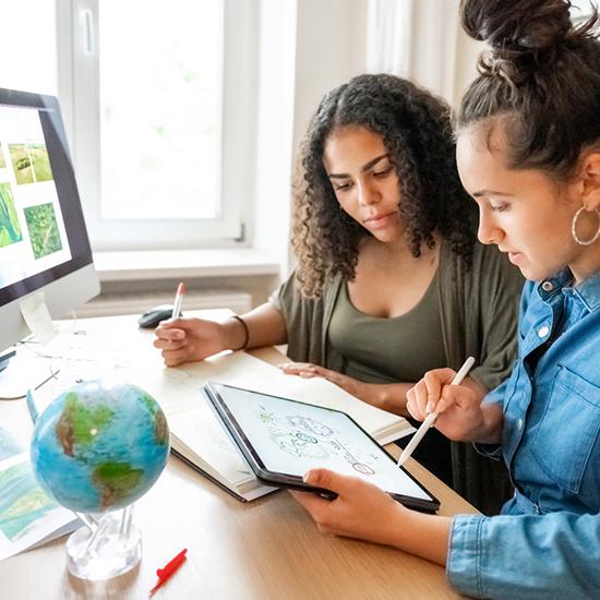 two women working on a project using a computer